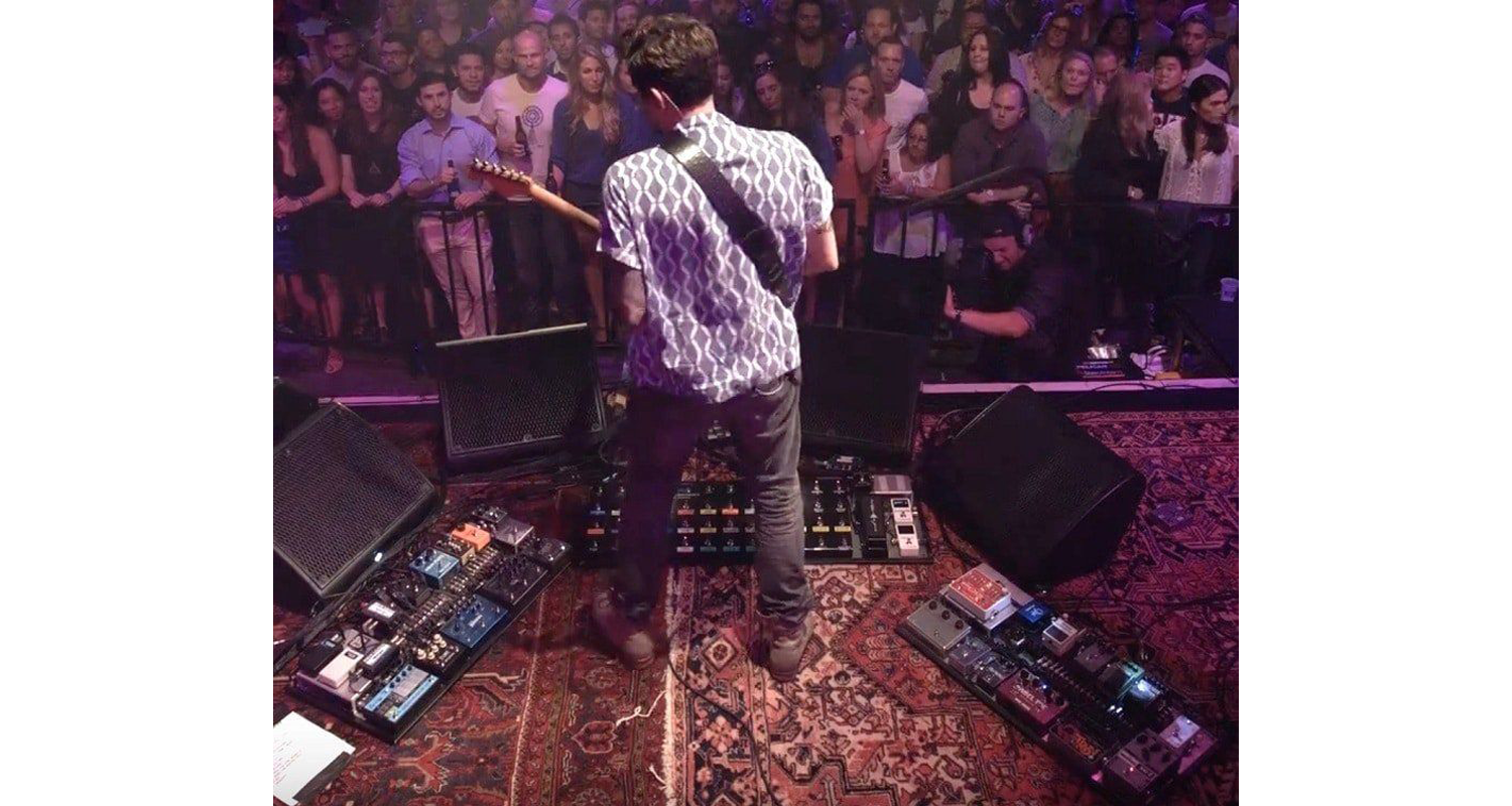 Rugs and Rockers: The Strange Bond Between Persian Rugs and Rock’n’Roll 7 John Mayer standing onstage over an elaborate pedalboard setup anchored by a classic Persian carpets during a live performance (c. 2013).